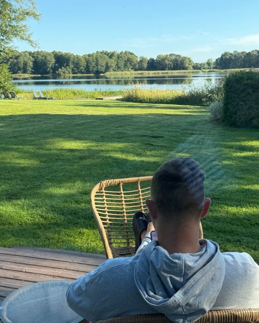 Maciej Aniserowicz siedzi w wiklinowym fotelu z widokiem na jezioro