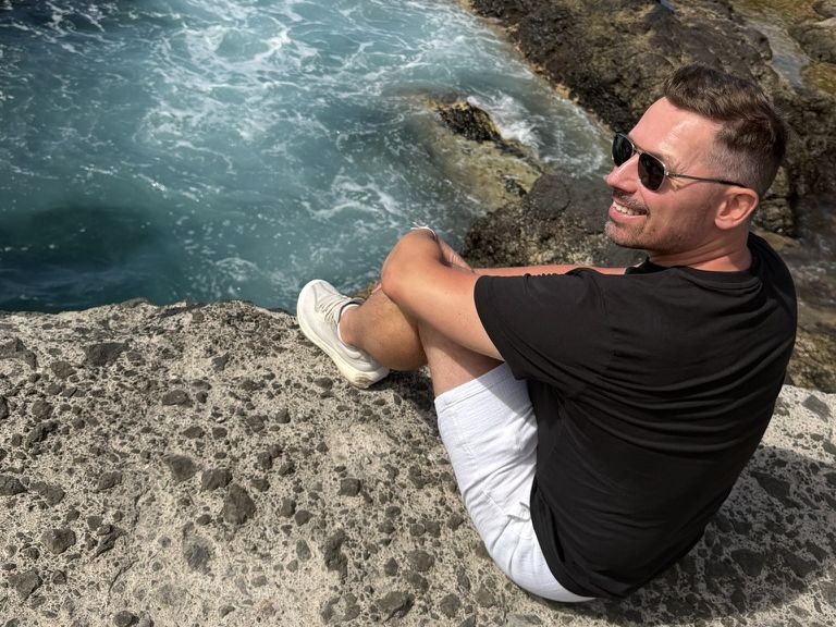 Maciej Aniserowicz siedzi na skale nad oceanem